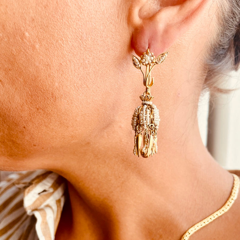 Close-up of a person wearing a gold earring with intricate design.