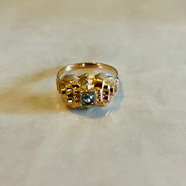 An 18 carat gold two-tone cocktail ring with a zirconia center stone, placed on a flat surface.