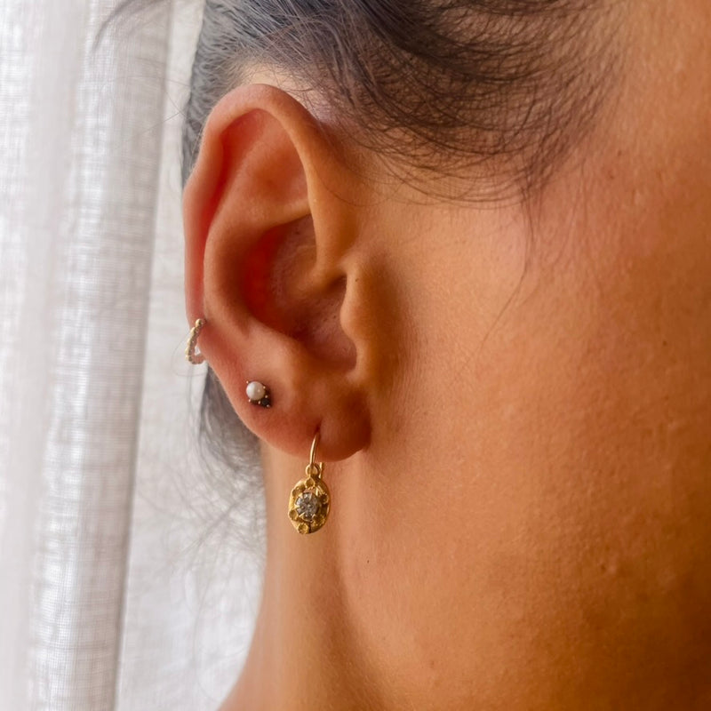 Close-up of an ear wearing gold earrings with a soft background | Deheb Jewellery Malta