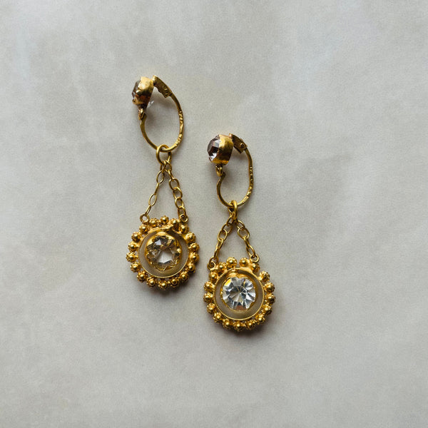A pair of chandelier style drop earrings set in gold and glass stones, suspended from fine chains.