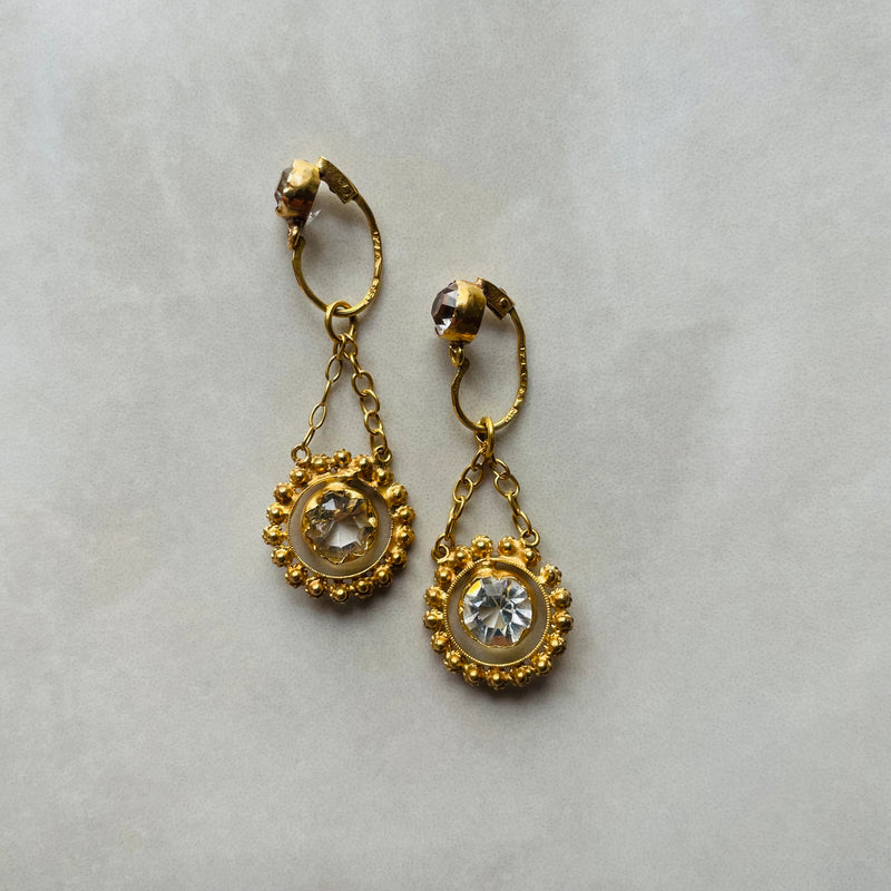 A pair of chandelier style drop earrings set in gold and glass stones, suspended from fine chains.