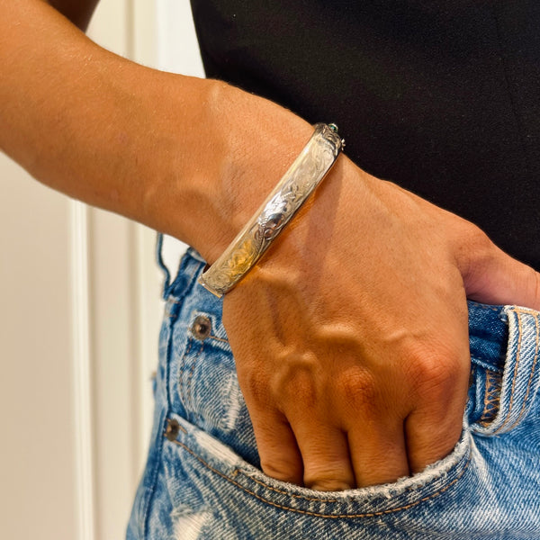 Hand wearing a silver bracelet with a textured design, holding a phone, against a neutral background | Deheb Jewellery Malta