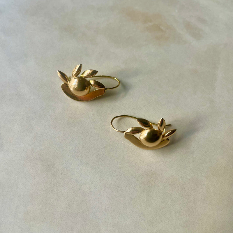 A pair of gold hoop earrings designed to resemble an abstract interpretation of an eye with eyelashes.