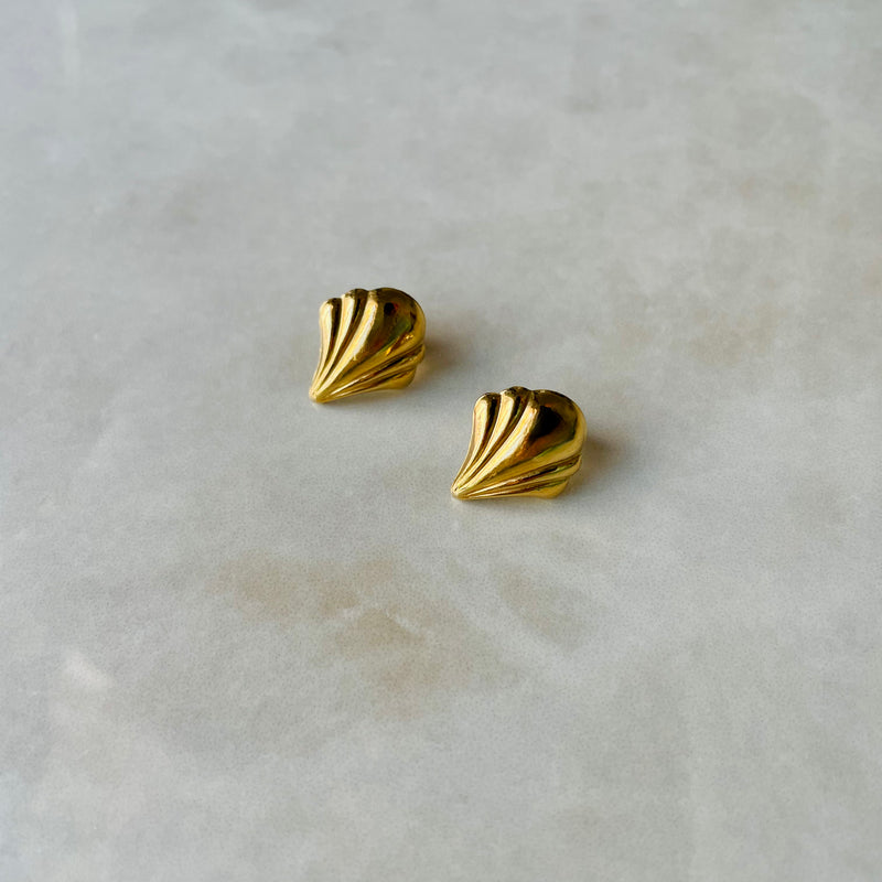 Pair of gold fan-shaped earrings on a light marble surface