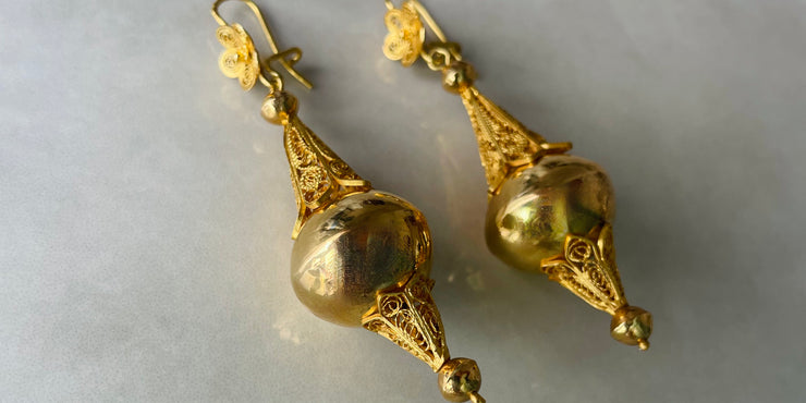 Pair of gold earrings on a light gray background