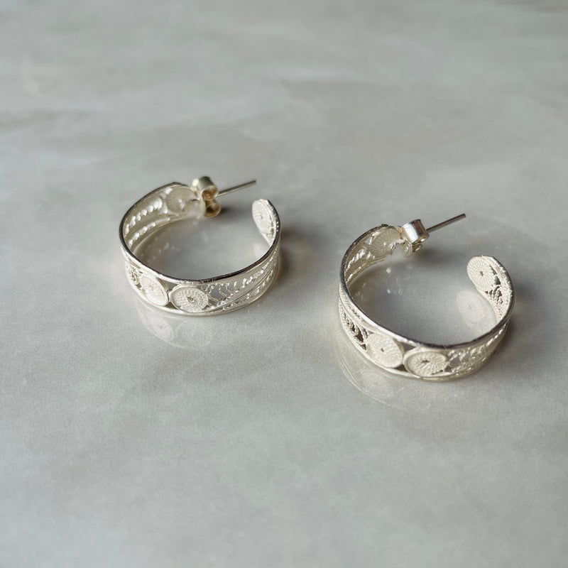Silver hoop earrings on a light grey surface | Deheb Jewellery Malta