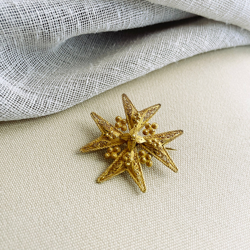 Gold star-shaped brooch on a textured fabric background