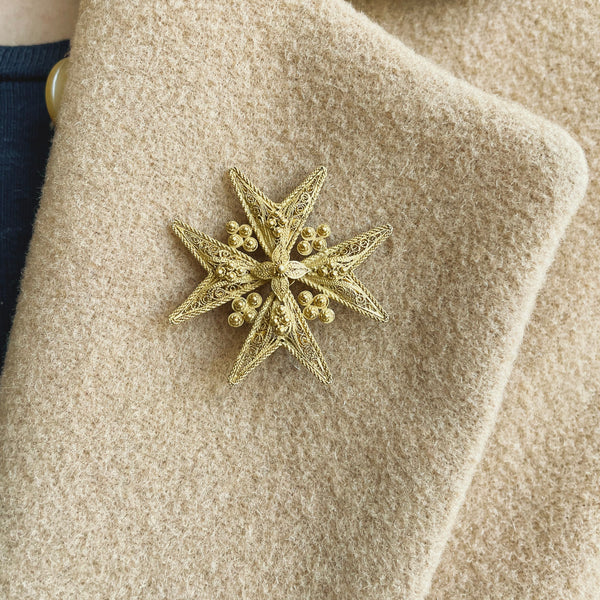 Gold star-shaped brooch on a beige coat