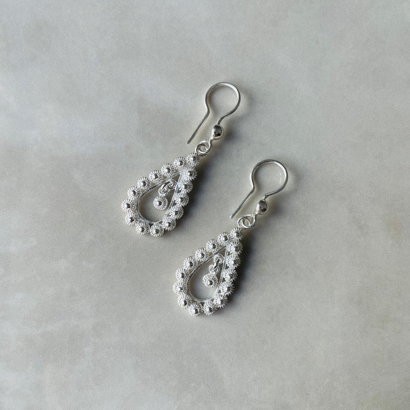 Silver teardrop earrings with intricate designs on a light gray background | Deheb Jewellery Malta