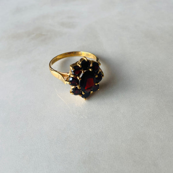 Gold ring with a garnet stone on a light gray background | Deheb Malta Jewellery