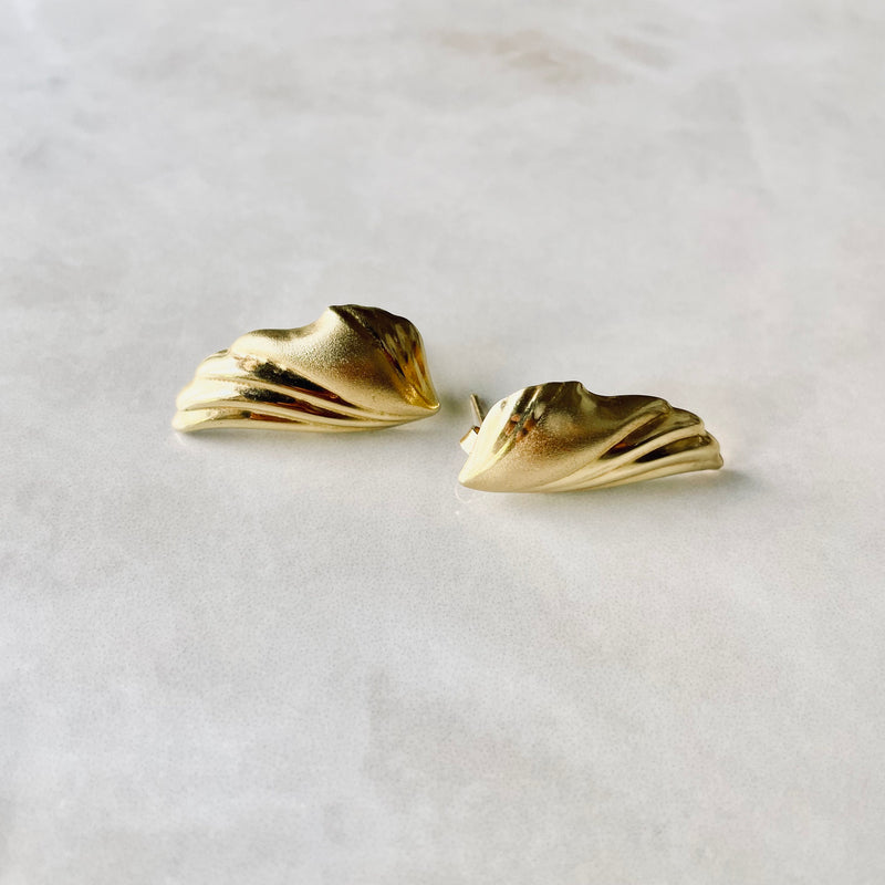 Gold earrings on a light gray background