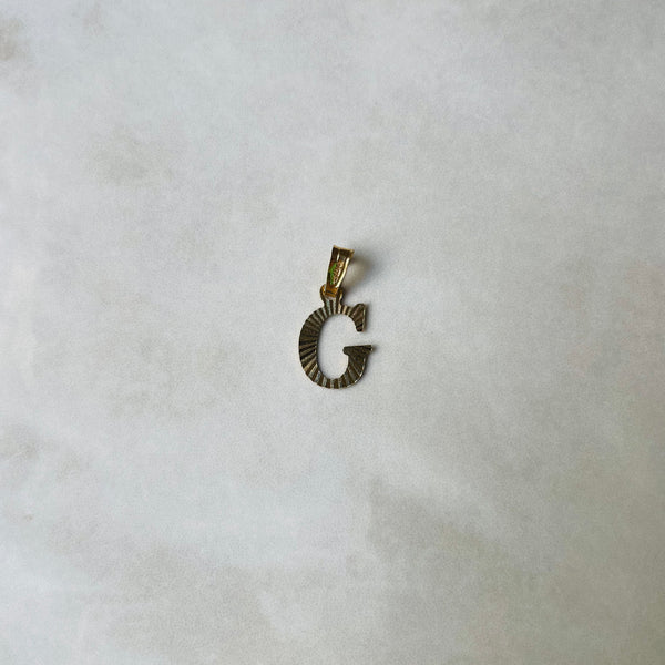 Gold letter 'G' pendant on a light gray background