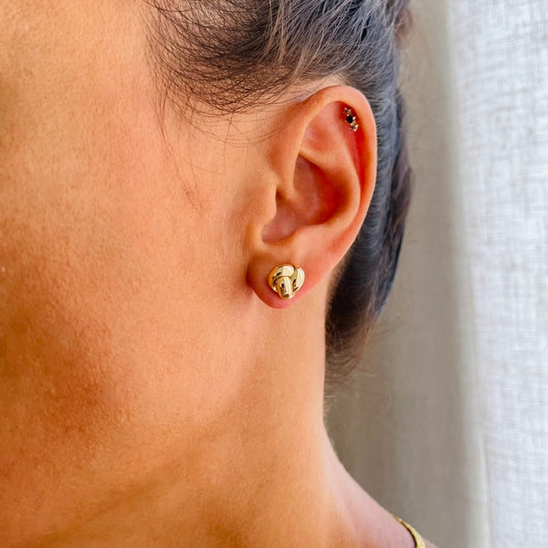 Close-up of a person wearing gold knot earrings | Deheb Jewellery Malta
