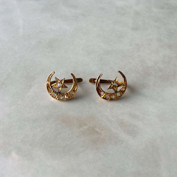 Gold earrings with star and moon design on a light gray background