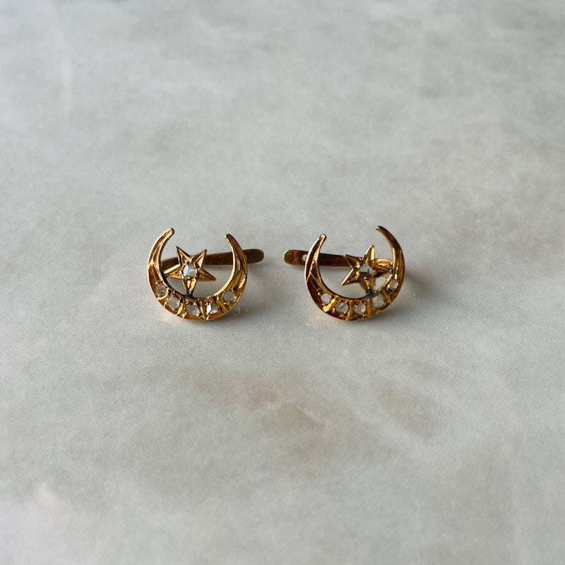 Gold earrings with star and moon design on a light gray background