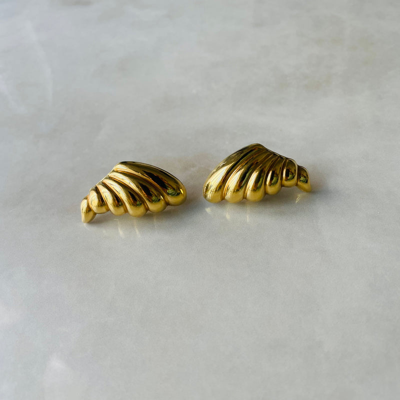 Pair of gold cornucopia-shaped earrings on a light gray background