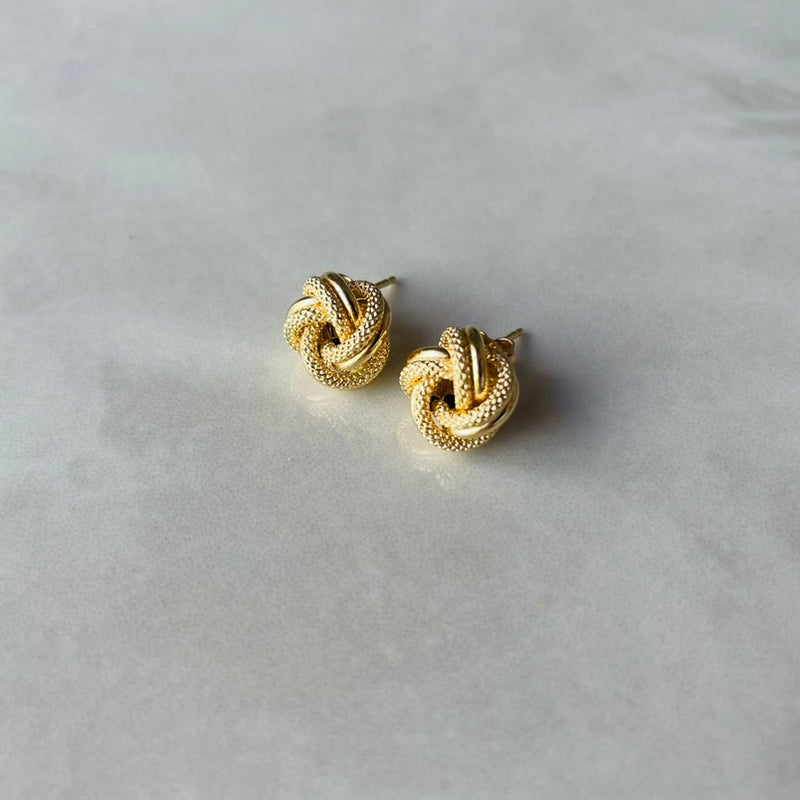 Pair of gold knot earrings on a light grey background |Deheb Malta Jewellery