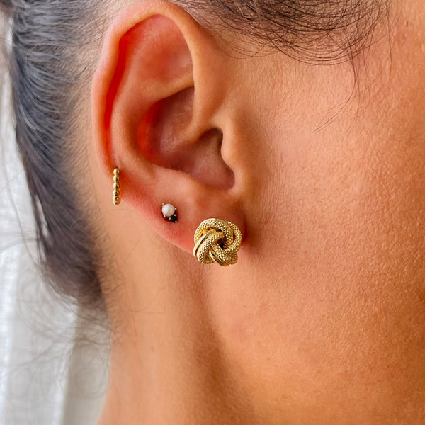 Close-up of an ear wearing a gold knot earring on model | Deheb Jewellery Malta