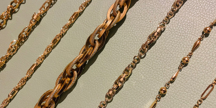 Gold chains of different designs on a light gray background