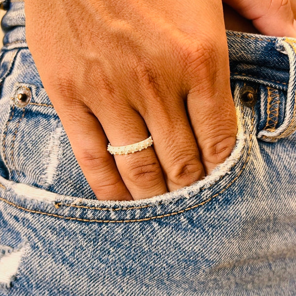 Close-up of a hand wearing a ring on blue denim jeans | Deheb Jewellery Malta