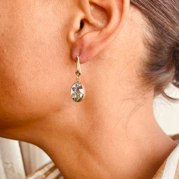 Close-up of an ear wearing a gold earring with a green gemstone.