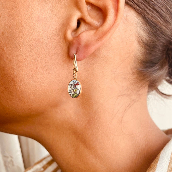Close-up of an ear wearing a gold earring with a green gemstone.