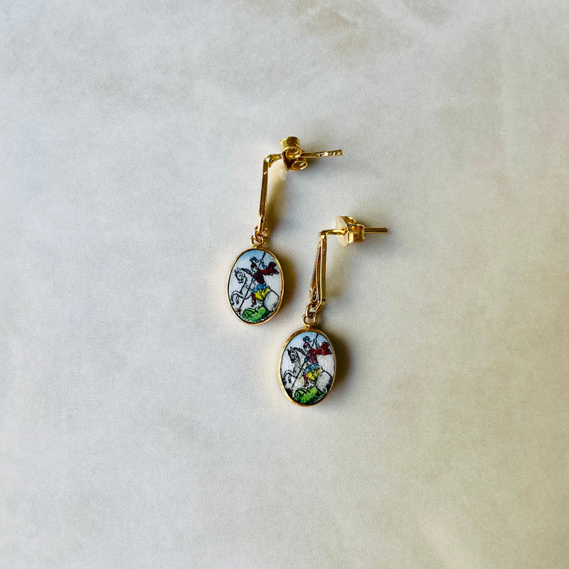 Pair of gold earrings with colorful designs on a light background