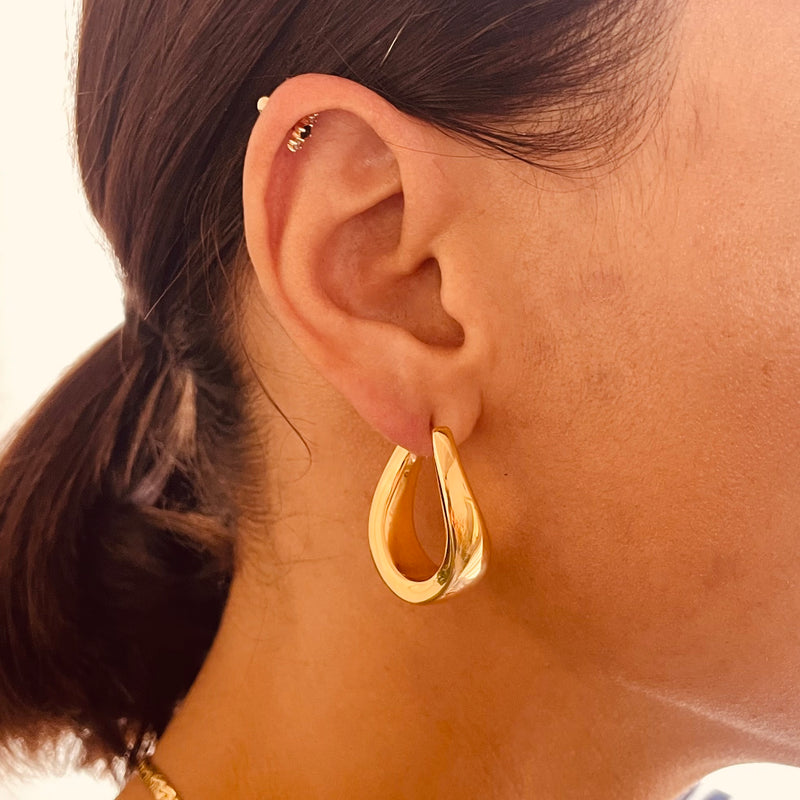 Gold hoop earring worn by a model