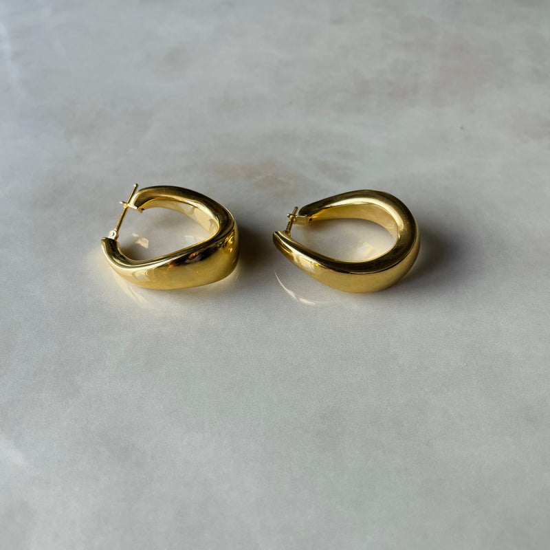 Pair of gold hoop earrings on a light gray background