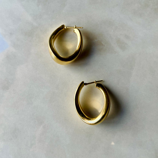 Pair of gold hoop earrings on a light gray background