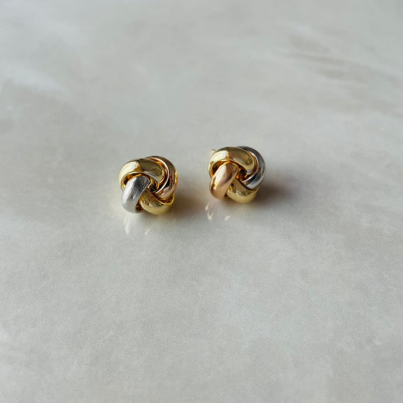 Pair of gold knot earrings on a light gray background | Deheb Malta Jewellery